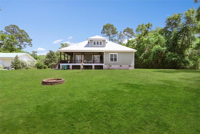 rear view of property featuring an outdoor fire pit, crawl space, a ceiling fan, a yard, and metal roof