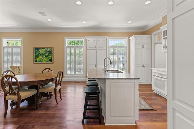 kitchen with a kitchen island with sink, white cabinets, crown molding, sink, and dark hardwood / wood-style floors