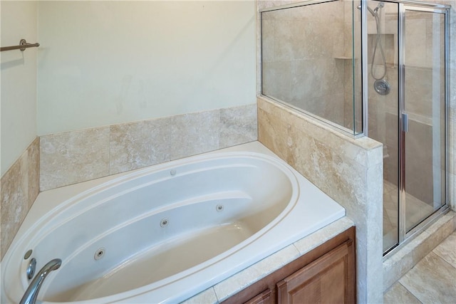 bathroom with a shower stall and a tub with jets