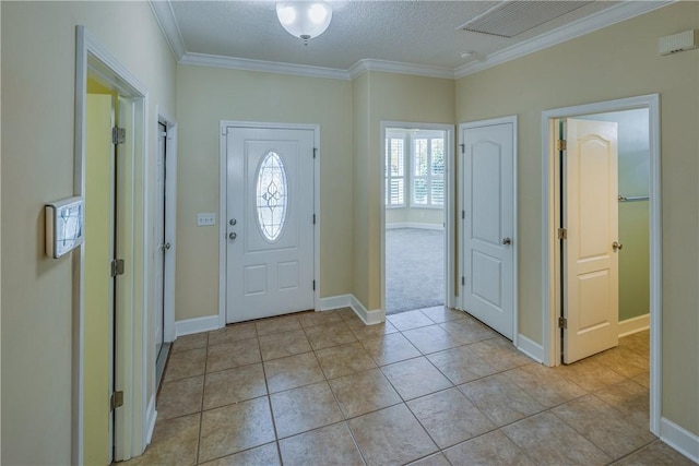 foyer featuring visible vents, baseboards, a textured ceiling, crown molding, and light tile patterned flooring