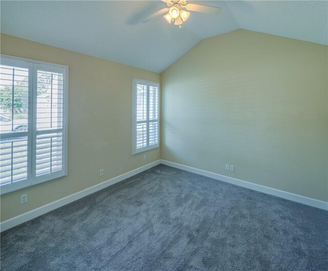 carpeted empty room featuring baseboards, a ceiling fan, and vaulted ceiling