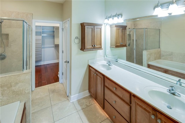 bathroom with a shower stall, tile patterned floors, double vanity, and a sink