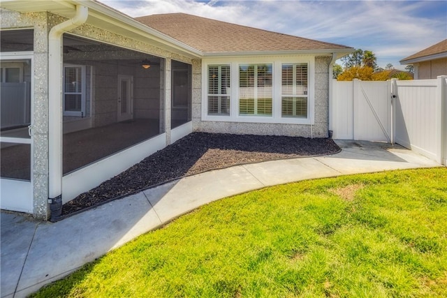 view of home's exterior with fence, a sunroom, a gate, and a lawn