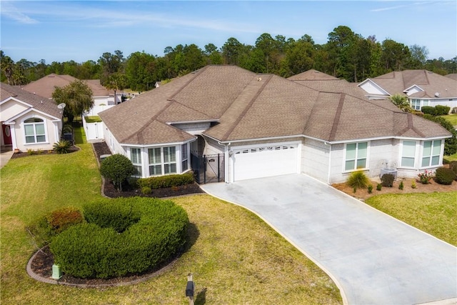 ranch-style house featuring driveway, a front lawn, a garage, fence, and a shingled roof