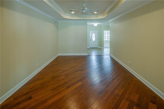 spare room featuring ornamental molding, a tray ceiling, a ceiling fan, and wood finished floors