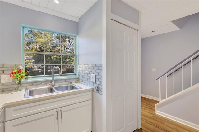 kitchen with backsplash, sink, white cabinets, and light hardwood / wood-style flooring