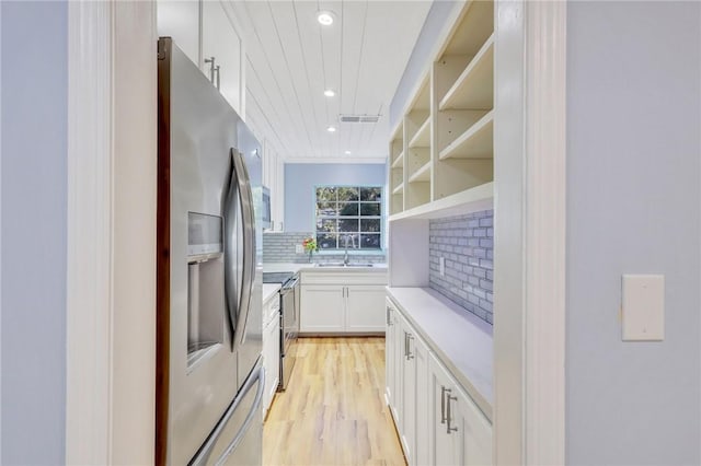 kitchen with white cabinetry, sink, backsplash, light hardwood / wood-style floors, and appliances with stainless steel finishes