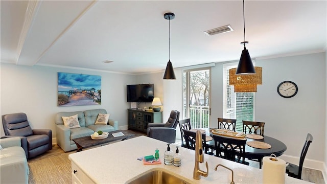 kitchen with crown molding, light hardwood / wood-style flooring, and hanging light fixtures