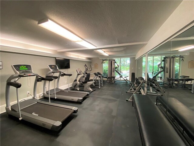 exercise room featuring a textured ceiling and baseboards