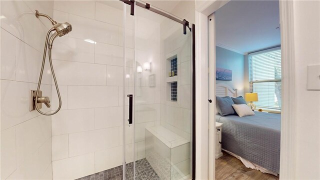 full bathroom featuring wood finished floors, ensuite bath, a stall shower, and ornamental molding