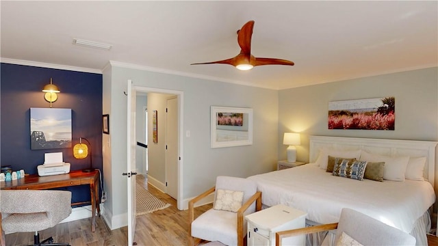 bedroom with wood finished floors, visible vents, baseboards, ceiling fan, and crown molding