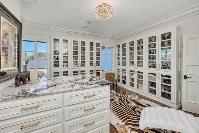 spacious closet featuring dark hardwood / wood-style flooring and an inviting chandelier