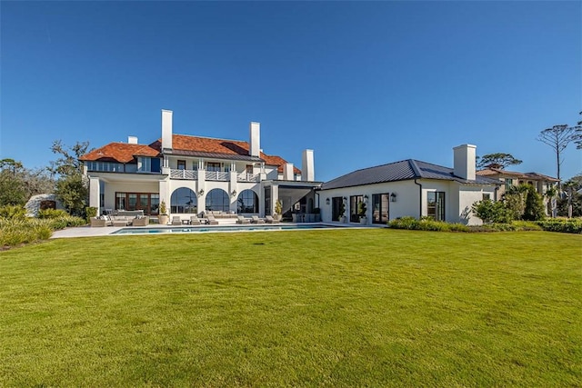 back of property featuring a balcony, a patio, and a lawn