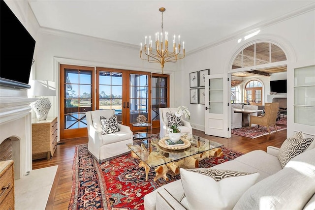 living room with an inviting chandelier, french doors, ornamental molding, wood-type flooring, and a premium fireplace