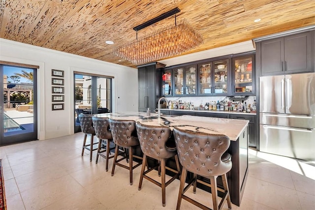 bar featuring light stone countertops, hanging light fixtures, stainless steel fridge, wooden ceiling, and sink