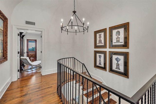 hallway featuring an inviting chandelier, hardwood / wood-style floors, and crown molding