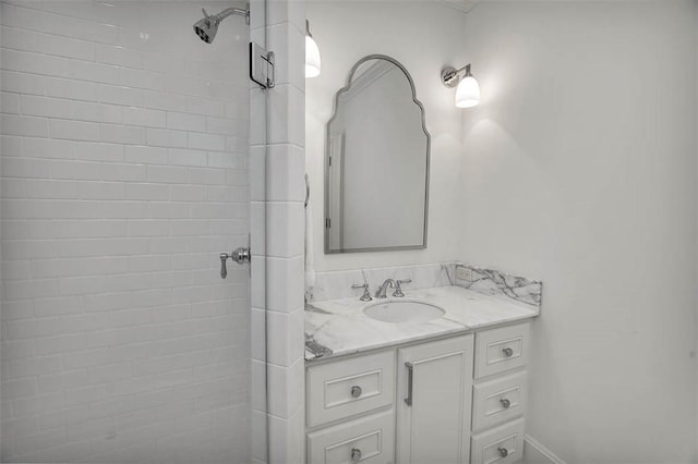 bathroom with a tile shower and vanity