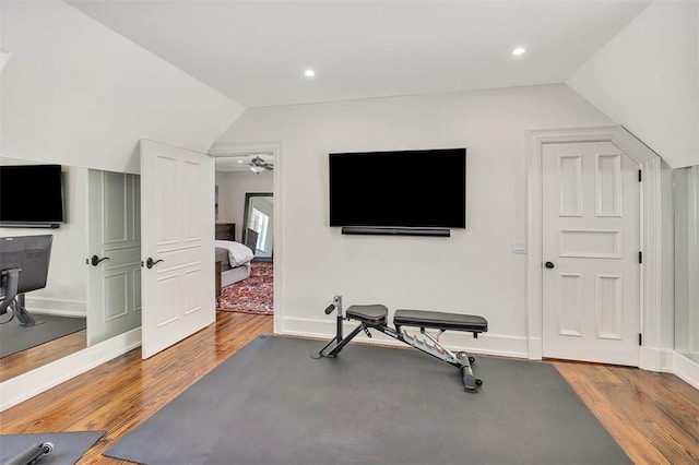 exercise room with vaulted ceiling, ceiling fan, and hardwood / wood-style floors