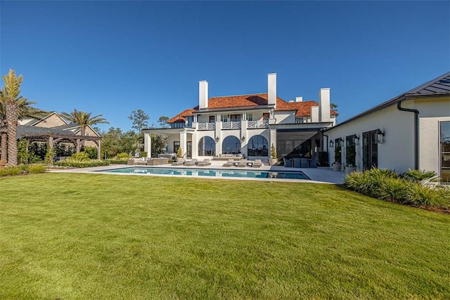 back of property with a balcony, a patio, and a lawn