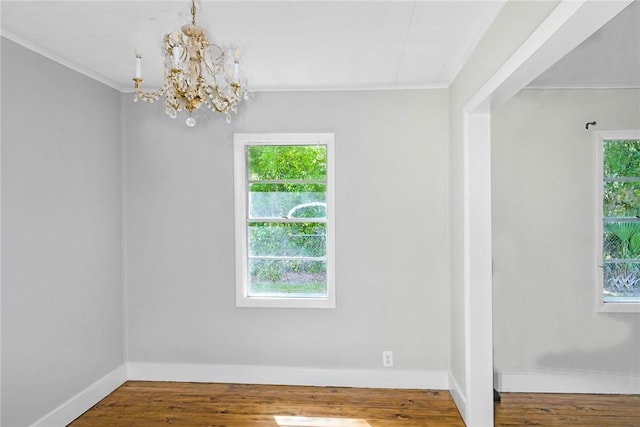 interior space featuring crown molding, a notable chandelier, wood finished floors, and baseboards