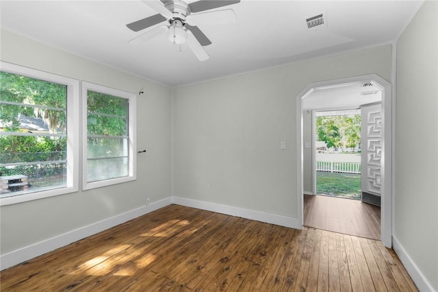 spare room with a ceiling fan, visible vents, baseboards, arched walkways, and hardwood / wood-style flooring