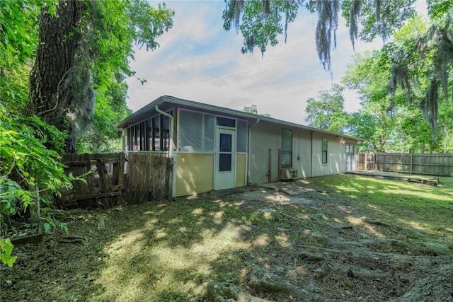 rear view of house with a fenced backyard, central air condition unit, a sunroom, and a lawn