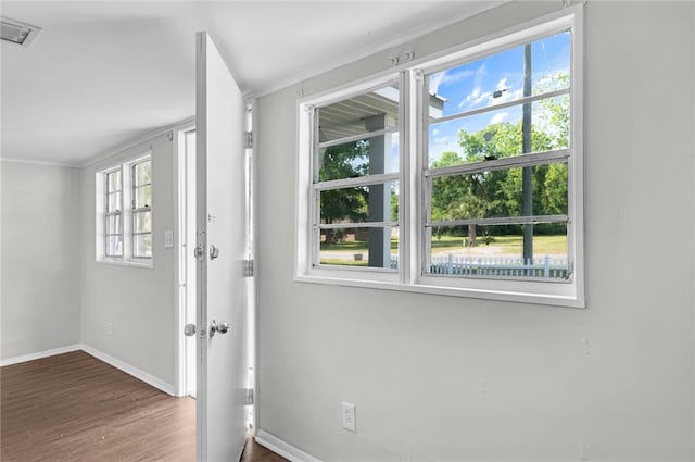 doorway featuring wood finished floors, crown molding, visible vents, and baseboards