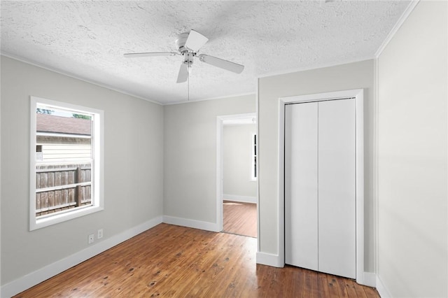 unfurnished bedroom featuring hardwood / wood-style floors, crown molding, a textured ceiling, and a closet