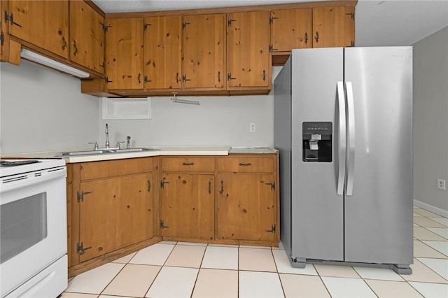 kitchen with brown cabinetry, stainless steel fridge, light countertops, white range with electric stovetop, and a sink