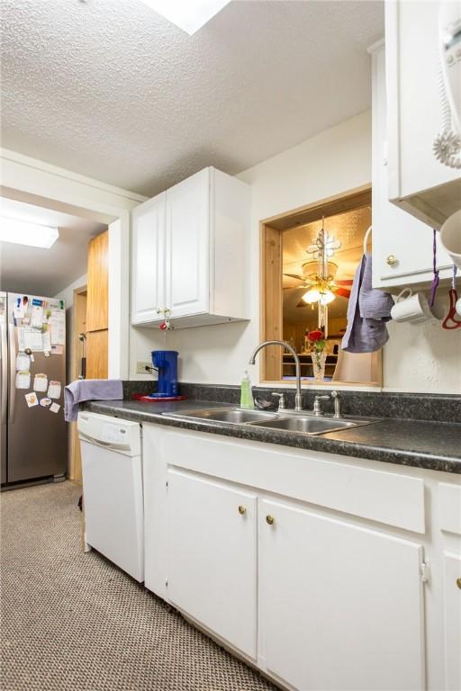2896 S Lakeview Dr, Waycross, GA 31503 - kitchen with freestanding refrigerator, dishwasher, a sink, white cabinets, and dark countertops