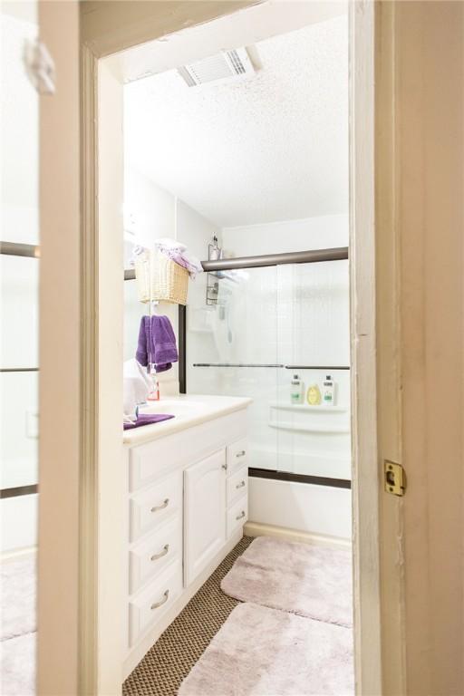 2896 S Lakeview Dr, Waycross, GA 31503 - full bathroom featuring vanity, bath / shower combo with glass door, and a textured ceiling