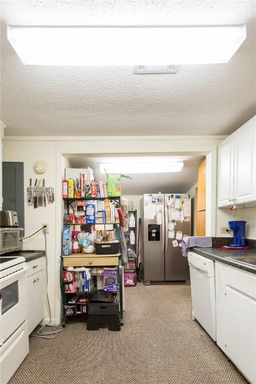 2896 S Lakeview Dr, Waycross, GA 31503 - kitchen featuring white appliances, dark countertops, white cabinets, light colored carpet, and a textured ceiling