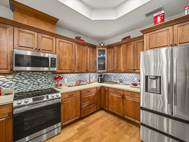108 Fox Run Dr, Brunswick, GA 31525 - kitchen with brown cabinetry, light countertops, appliances with stainless steel finishes, and light wood-style flooring