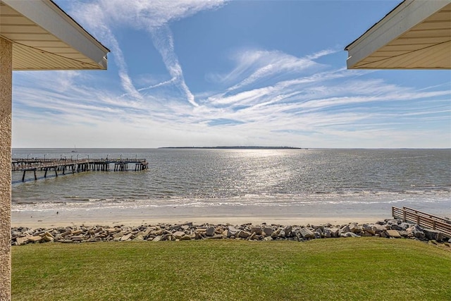 dock area featuring a view of the beach, a water view, and a yard