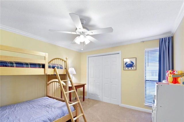 bedroom featuring ceiling fan, a textured ceiling, light carpet, a closet, and ornamental molding