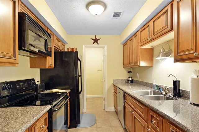 kitchen featuring light stone countertops, sink, a textured ceiling, light tile patterned floors, and black appliances