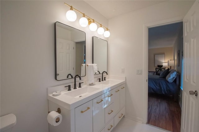 bathroom with double vanity, toilet, connected bathroom, and a sink