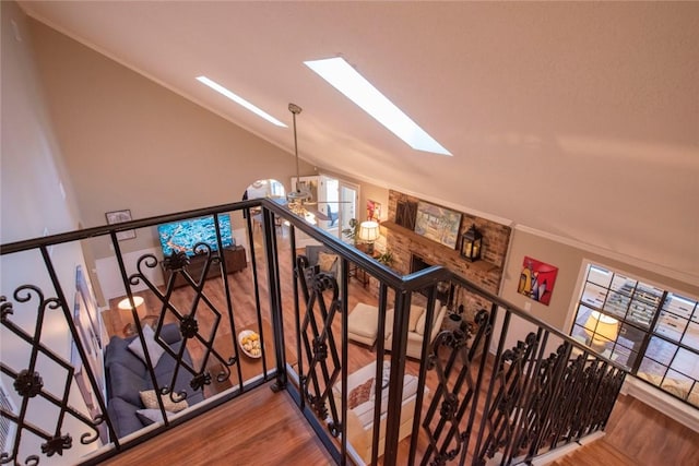 staircase featuring lofted ceiling with skylight, ornamental molding, and wood finished floors