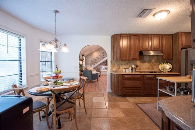 kitchen with visible vents, brown cabinets, under cabinet range hood, backsplash, and black electric stovetop