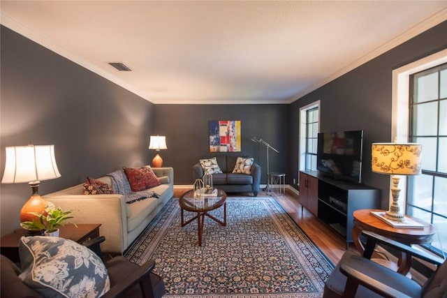 living area with visible vents, plenty of natural light, wood finished floors, and crown molding