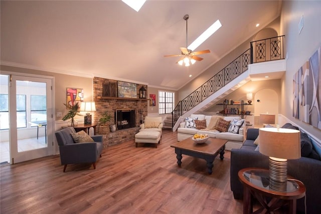 living room featuring stairs, crown molding, wood finished floors, and a fireplace