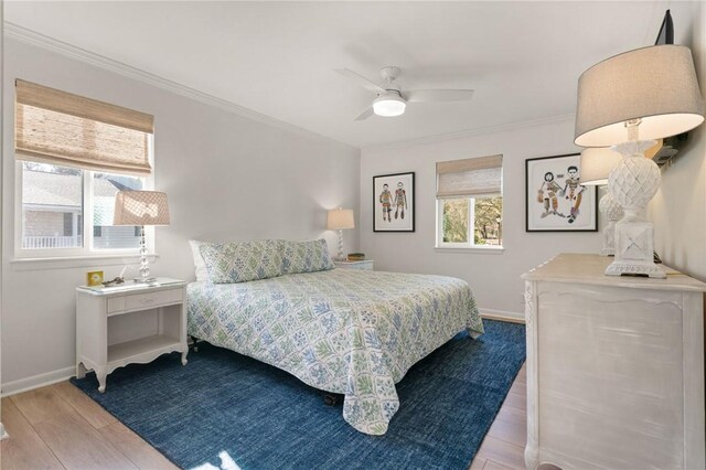 bedroom featuring ornamental molding, wood finished floors, baseboards, and a ceiling fan