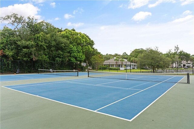 view of tennis court featuring community basketball court and fence