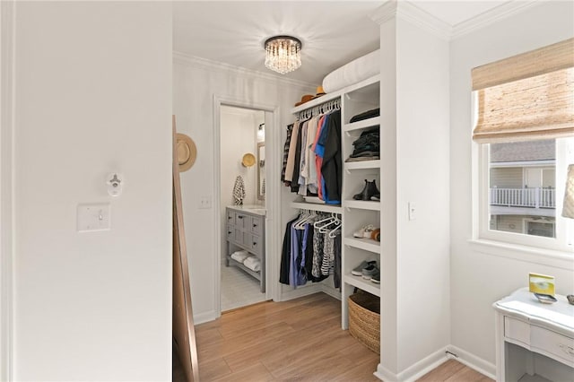 spacious closet with light wood-type flooring and a chandelier