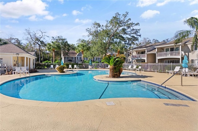 community pool with fence, a patio, and a residential view