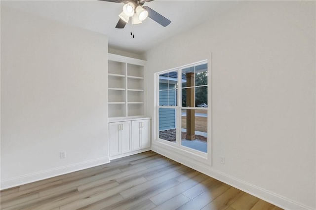 unfurnished room with ceiling fan, light hardwood / wood-style floors, and built in shelves