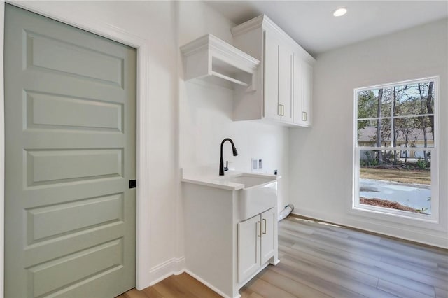 clothes washing area featuring hookup for an electric dryer, light hardwood / wood-style floors, sink, and hookup for a washing machine