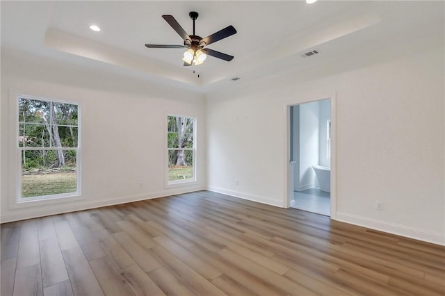 spare room featuring light hardwood / wood-style floors, a raised ceiling, and ceiling fan