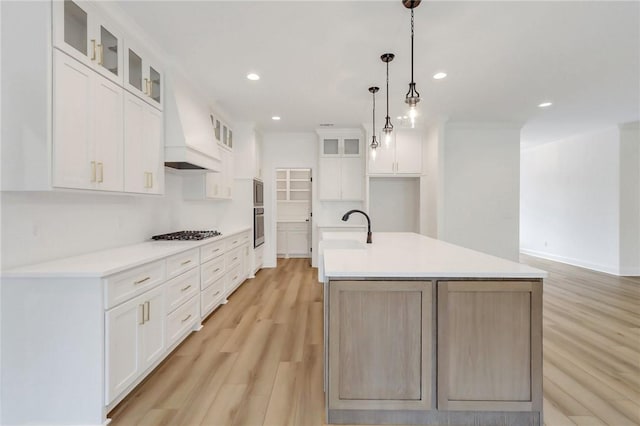 kitchen with white cabinetry and a kitchen island with sink