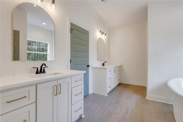 bathroom with wood-type flooring, vanity, and a tub to relax in